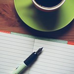 Image of cup of coffee, notebook with lined paper, and pen